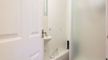 Un baño con lavamanos blanco, espejo y cabina de ducha de vidrio.