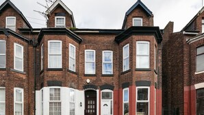 A two-story brick house with a bay window, a front door, and a small porch. - Short Term Shared R&R In Chorlton (Manchester)