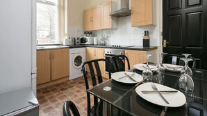 A compact kitchen with wooden cabinets, a built-in oven, a microwave, and a washing machine. - Short Term Shared R&R In Chorlton (Manchester)