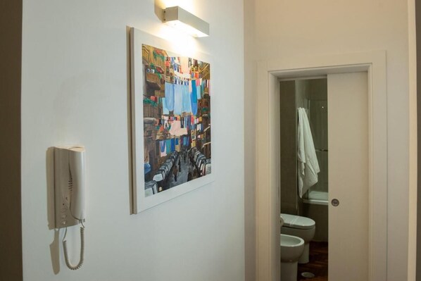 A bathroom with a white toilet, a shower, and a wall-mounted telephone.