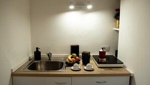 Eine moderne Küche mit Spüle aus Edelstahl, Obstschale, Kaffeemaschine und Waage.