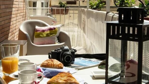Ein Balkon mit einem Tablett Frühstücksgebäck, darunter Croissants, eine Kamera und eine Laterne.