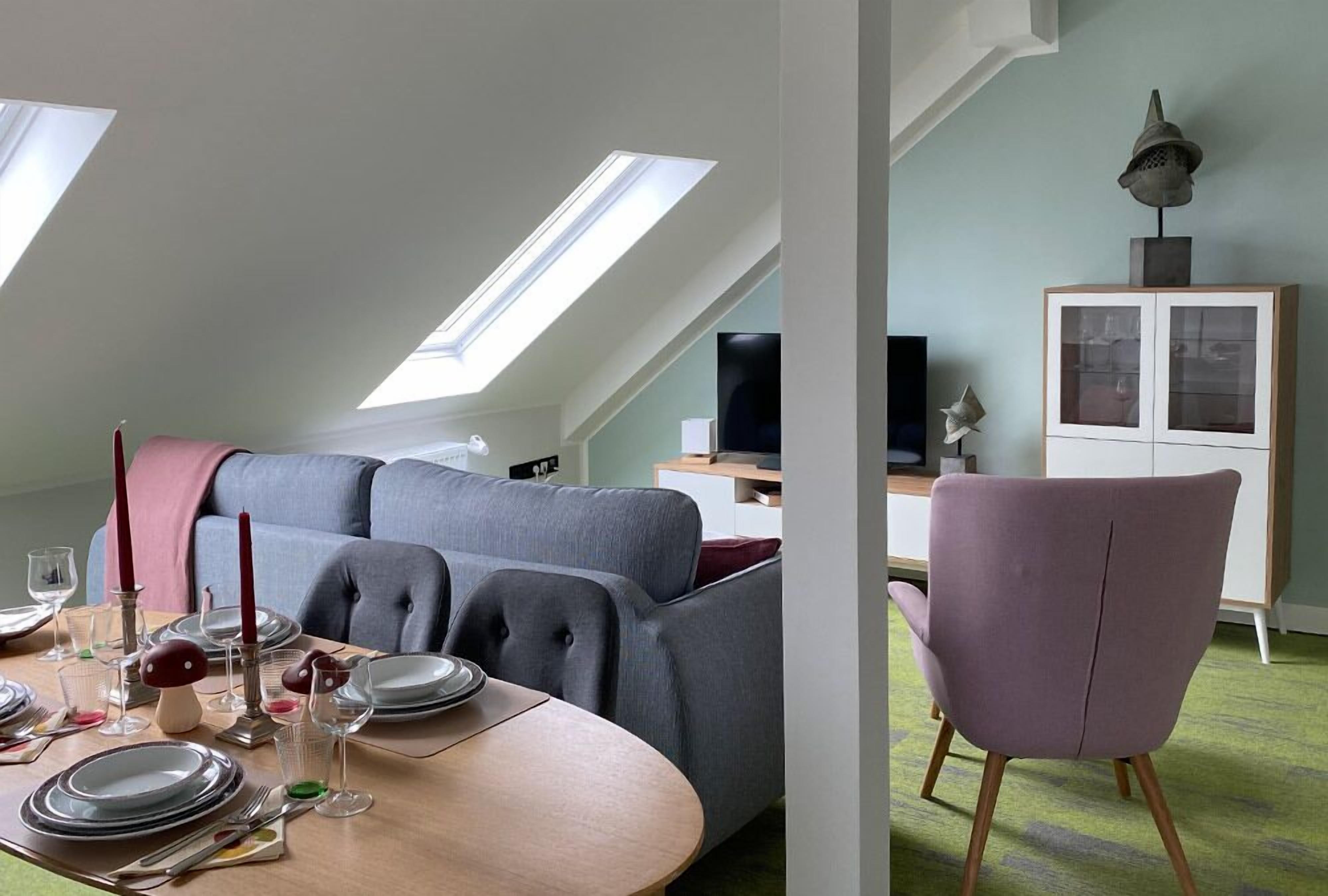 Un coin repas avec une table dressée pour quatre personnes, un canapé et un meuble avec des portes en verre.
