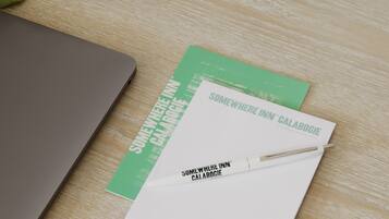 A laptop, a notebook, and a pen on a wooden surface.
