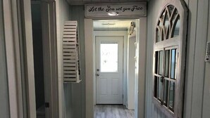 Un pasillo con una puerta al final, un cartel sobre ella y una ventana en la pared derecha.