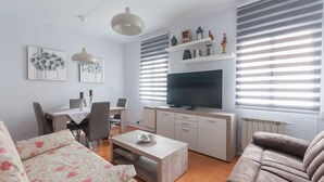 Una sala de estar moderna con sofá, mesa de centro, televisor y comedor.