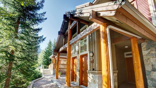 A wooden building with a stone foundation, large windows, and a covered walkway.
