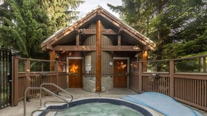 A wooden cabin with a hot tub and a deck.