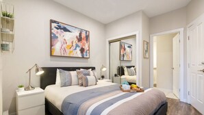 A bedroom with a bed, bedside tables, a mirror, and artwork on the walls.