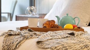 Ein Hotelzimmer mit einem Bett, einem Tablett mit Croissants, einem Teekessel und einer Tasse.