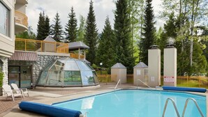 Ein Poolbereich mit einem in Glas eingefassten Whirlpool, Liegestühlen und einem Schild, das das Springen verbietet.
