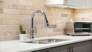 A modern kitchen with a stainless steel sink, a brick backsplash, and a built-in oven. - NEW! 2BR Townhouse: Private HotTub, Free Parking (Whistler)