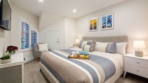 A modern bedroom with a large bed, bedside tables, a TV, and artwork on the walls. - NEW! 2BR Townhouse: Private HotTub, Free Parking (Whistler)