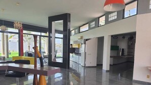A spacious, modern kitchen with a large island, a dining area with a table and chairs, and a view of the outdoors through large windows. - Villa saly joseph (M'bour)