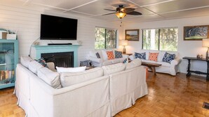Ein Wohnzimmer mit Kamin, zwei Sofas, einem Fernseher und einem Deckenventilator.