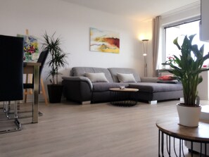 Ein modernes Wohnzimmer mit einem grauen Sofa, einem Couchtisch und einem Gemälde an der Wand.