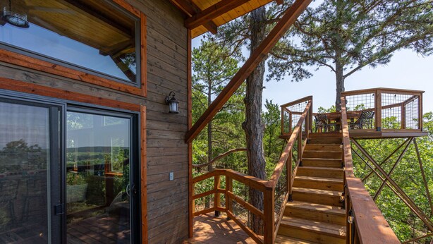Una terraza de madera con una escalera que lleva a una casa en el árbol.