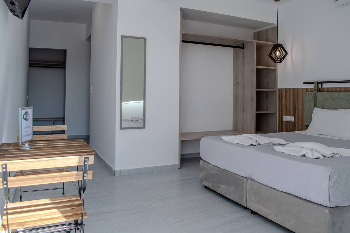 Un dormitorio moderno con una cama, una mesa de madera, un espejo y estanterías empotradas.