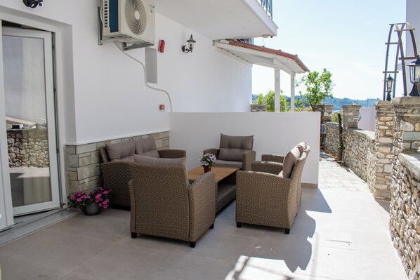 Un patio al aire libre con mobiliario de mimbre, un muro de piedra y vistas del paisaje.