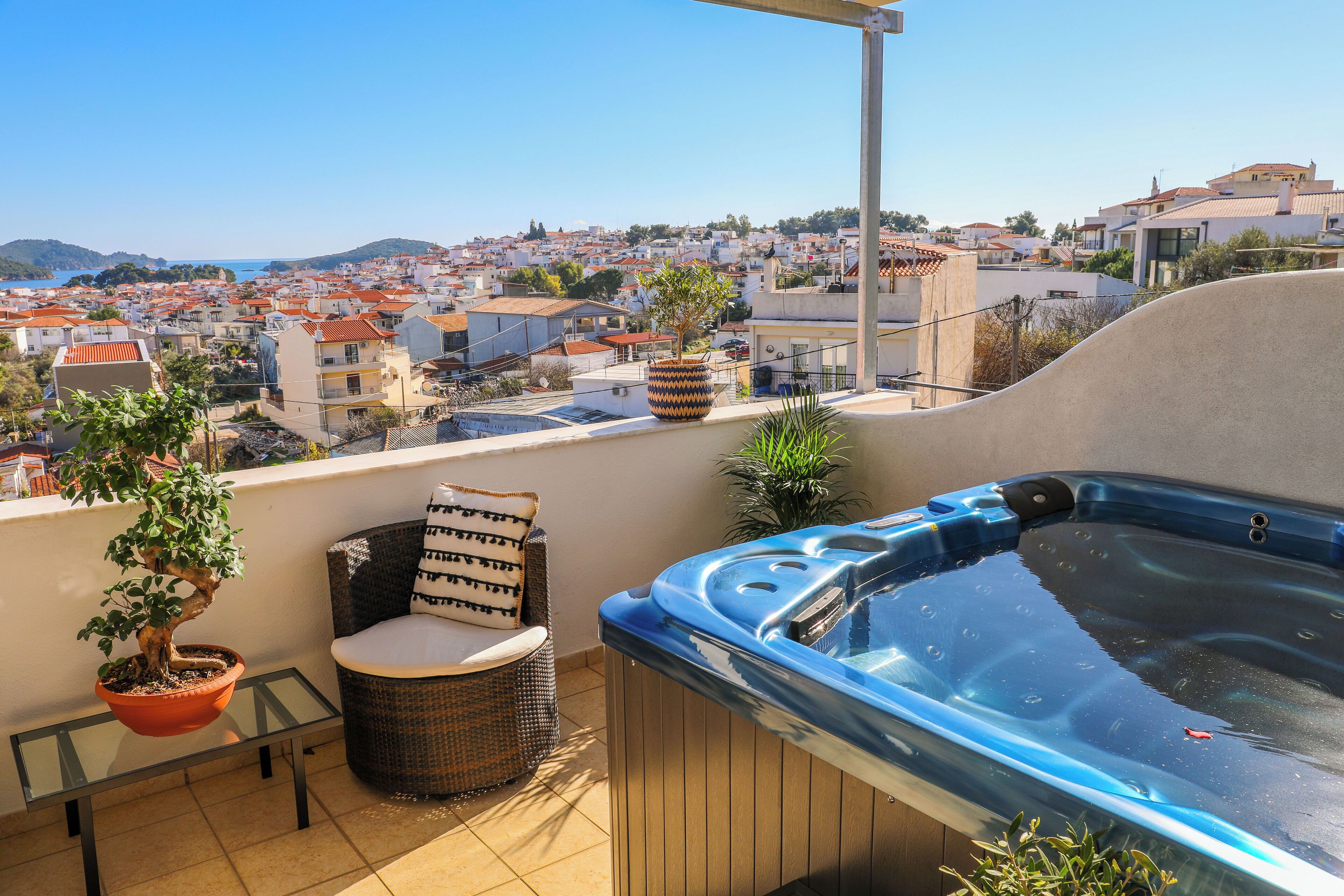 A balcony with a hot tub, a potted plant, and a wicker chair.