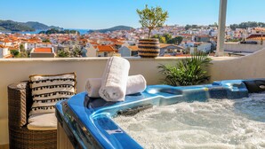 A hot tub with towels on a balcony overlooking a coastal town. - La Fleur (Skiathos)