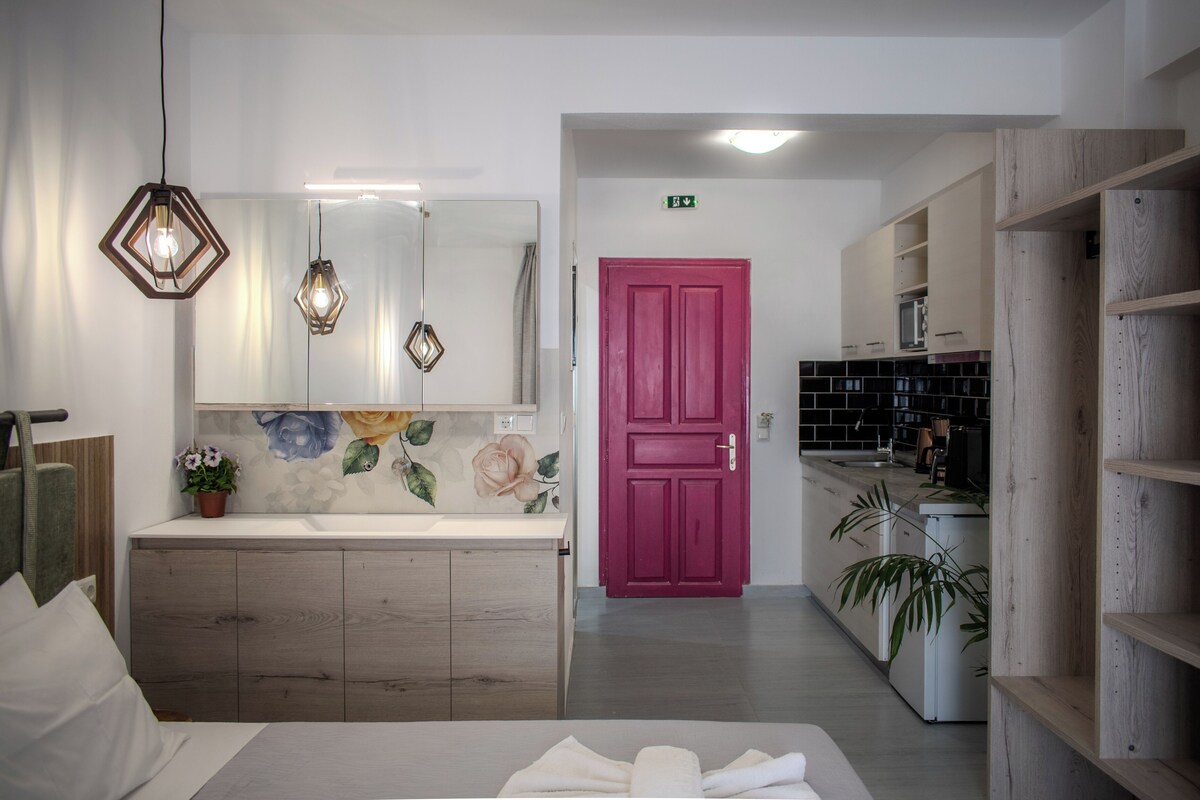 Un baño moderno con un espejo grande, armarios de madera, una puerta rosa y una zona de lavamanos.