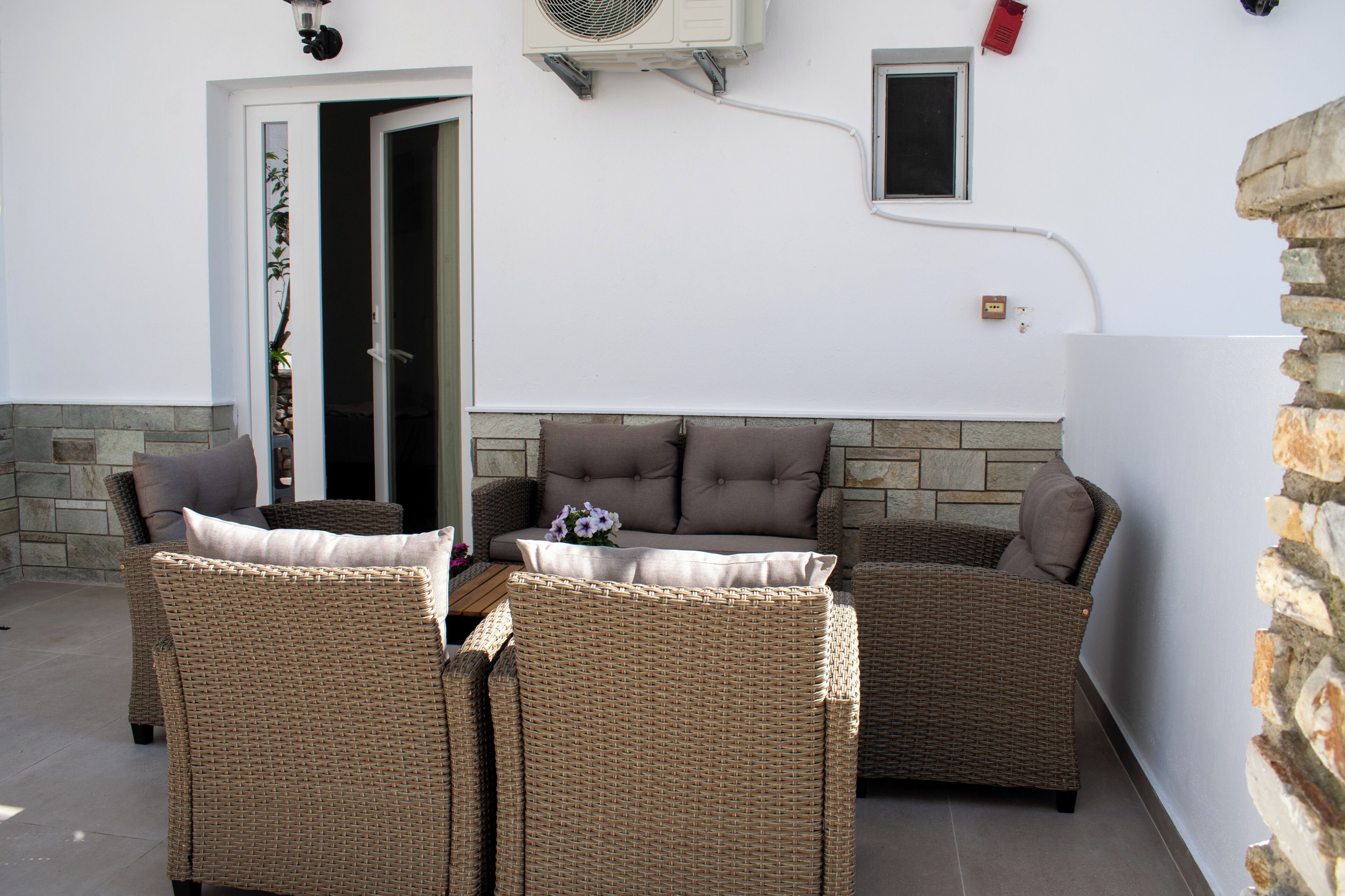 An outdoor seating area with wicker furniture and a stone wall.