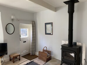 A living room with a black wood-burning stove, a television, a wicker basket, and a framed map on the wall. - Cottage with pretty garden and views. 2 mins from cobbled square, pubs/amenities (Skipton)