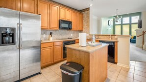 A kitchen with wooden cabinets, stainless steel appliances, a microwave, and a dishwasher. - Spacious Townhome With KING SUITE&Spa Tub (Houston)