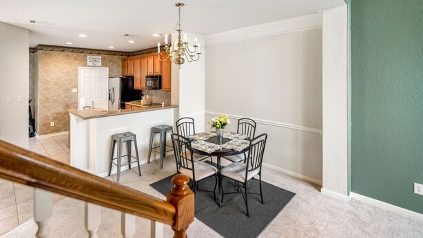 A modern kitchen with wooden cabinets, a central island, and a dining area with a round table and chairs. - Spacious Townhome With KING SUITE&Spa Tub (Houston)
