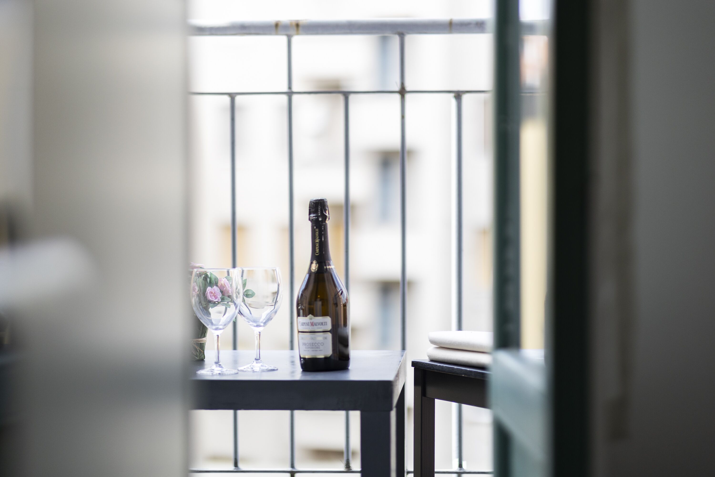 A balcony with a table, a bottle of wine, and two glasses.