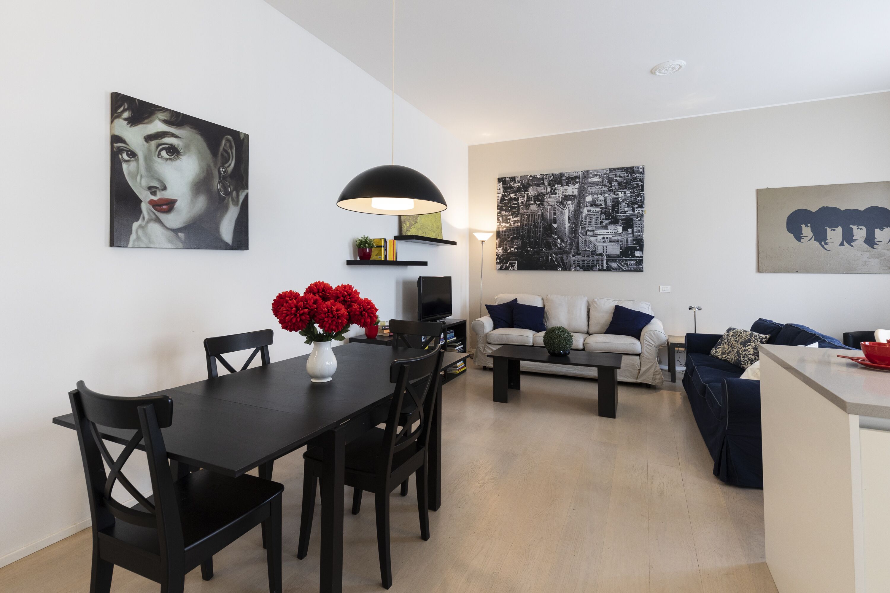 A modern living room with a dining table, black chairs, a sofa, and a coffee table.