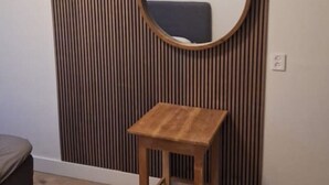 A room with a wooden slat wall, a round mirror, and a small wooden table.