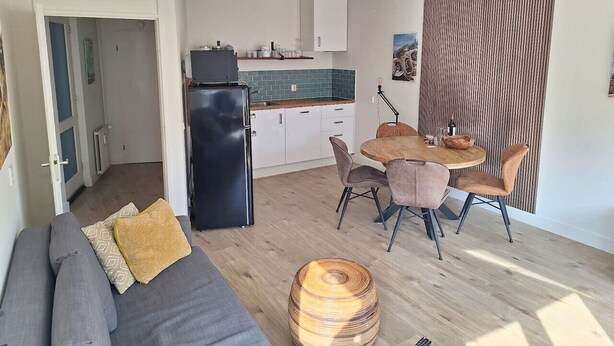 A compact living space with a kitchenette, a dining area, and a sofa with cushions.