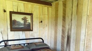 A single bed with a metal frame, a quilt with a geometric pattern, and a framed picture on the wall. - S and H Tack Room Enjoy a peaceful getaway (Sparta)