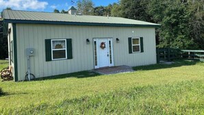 A single-story building with a green door, two windows with shutters, and a small porch area. - S and H Tack Room Enjoy a peaceful getaway (Sparta)