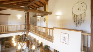 A spacious interior with wooden beams, a chandelier, and a dreamcatcher on the wall. - Au Temps Suspendu - Large Gîte 16 People - Pyrenees (Saint-Martin-d'Oydes)
