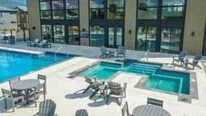 A modern hotel with a pool area featuring multiple swimming pools, lounge chairs, and tables. - LUX Modern Retreat: Hot tub & Pool, Perfect Location! (Whitefish)