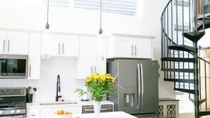 A modern kitchen with white cabinets, a central island with stools, a refrigerator, and a microwave. - LUX Modern Retreat: Hot tub & Pool, Perfect Location! (Whitefish)