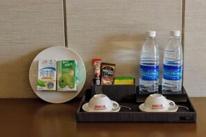 A tray with a plate, two cups, two bottles of water, a Nescafe coffee packet, and two boxes of milk.