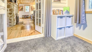 Ein gemütliches Zimmer mit Holzbalkendecke, Steinwand und Bücherregal mit Büchern und einem Poster.