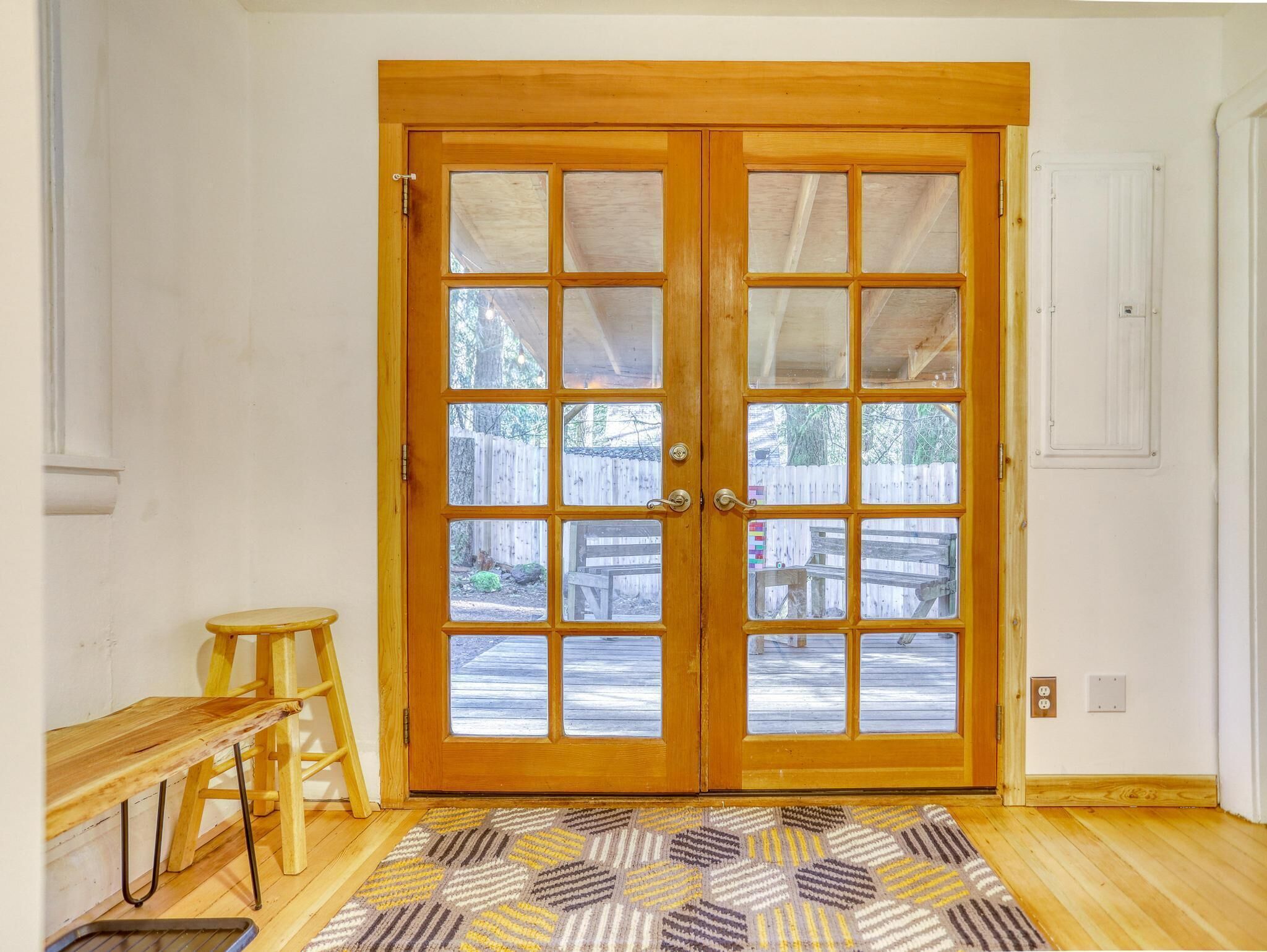 Una doppia porta in legno con pannelli di vetro, una panca di legno, una scala e un tappeto decorato.