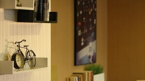 A modern interior with a bookshelf, a bicycle, a sofa, and a table. - IU Hotel (Chongqing Longtou Temple North Railway Station) (Chongqing)