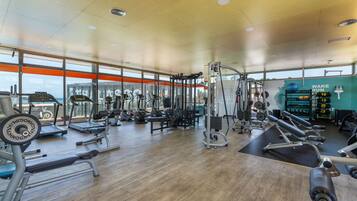 A gym with various exercise equipment, large windows, and a motivational sign.
