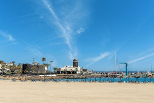 Una playa con tumbonas, una masa de agua y un edificio con cúpula.