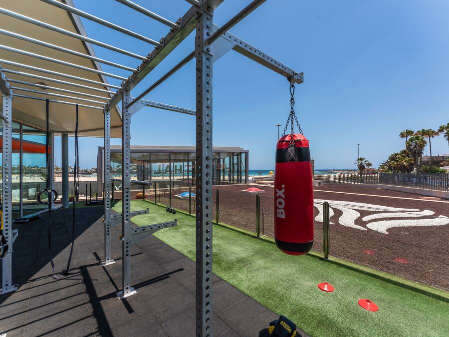 Une salle de sport équipée d’appareils d’exercice en plein air, d’un sac de frappe et offrant une vue dégagée sur l’océan.