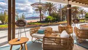 Un espace extérieur aménagé avec des meubles en osier et offrant une vue sur la plage.