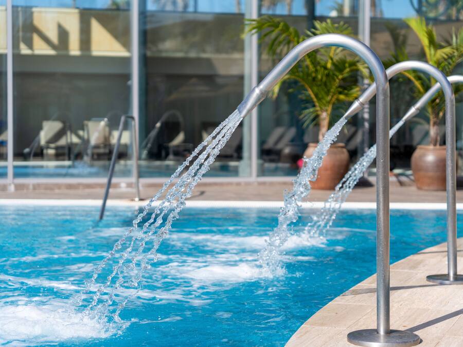 Ein Pool mit klarem Wasser und einer Springbrunnenanlage aus Metall.