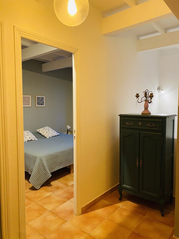 Een kamer met een bed, een kast en een deur naar een andere ruimte.
