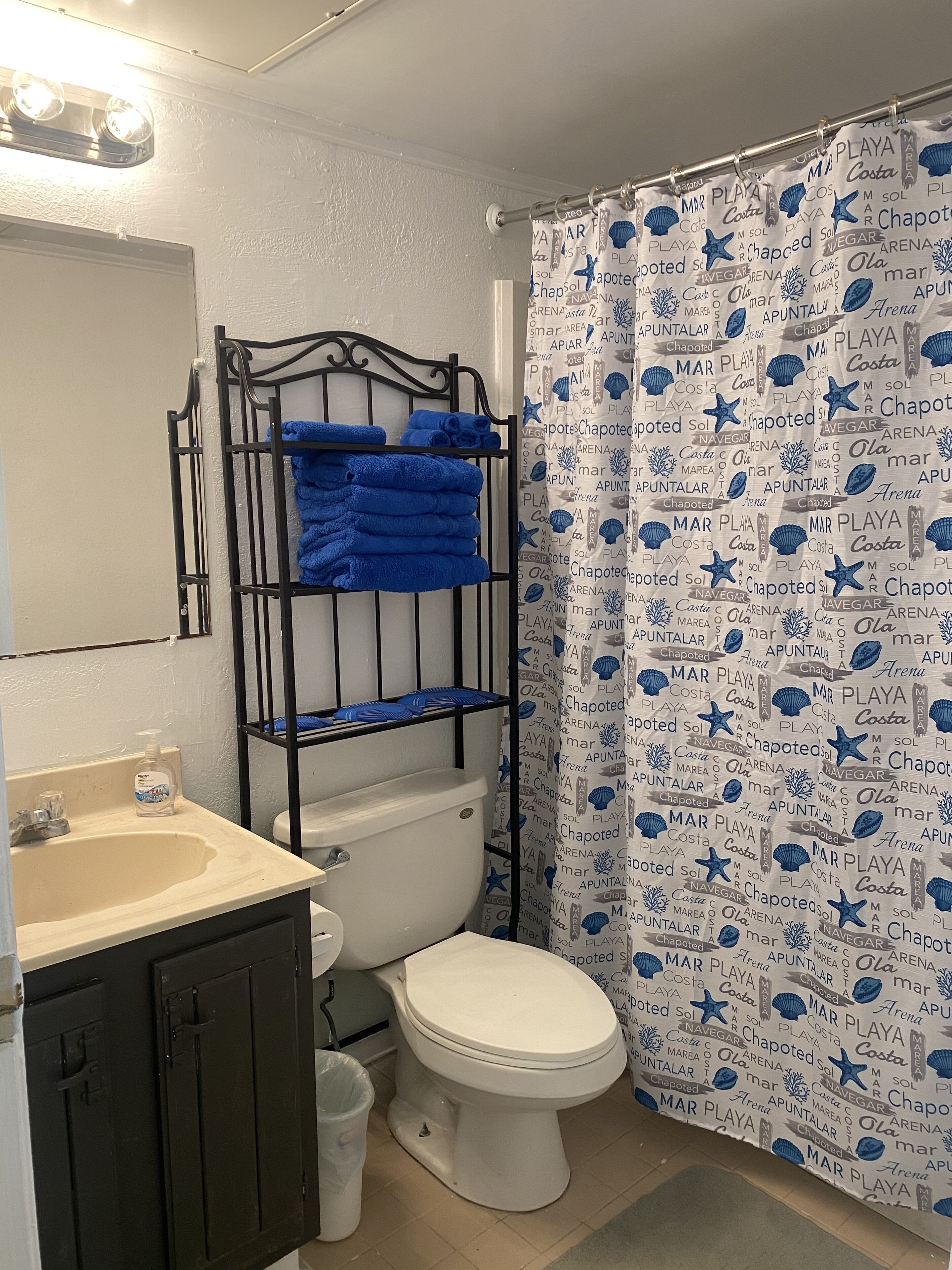 Une salle de bain équipée de toilettes, d’un lavabo et d’un rideau de douche sur le thème de la marine.